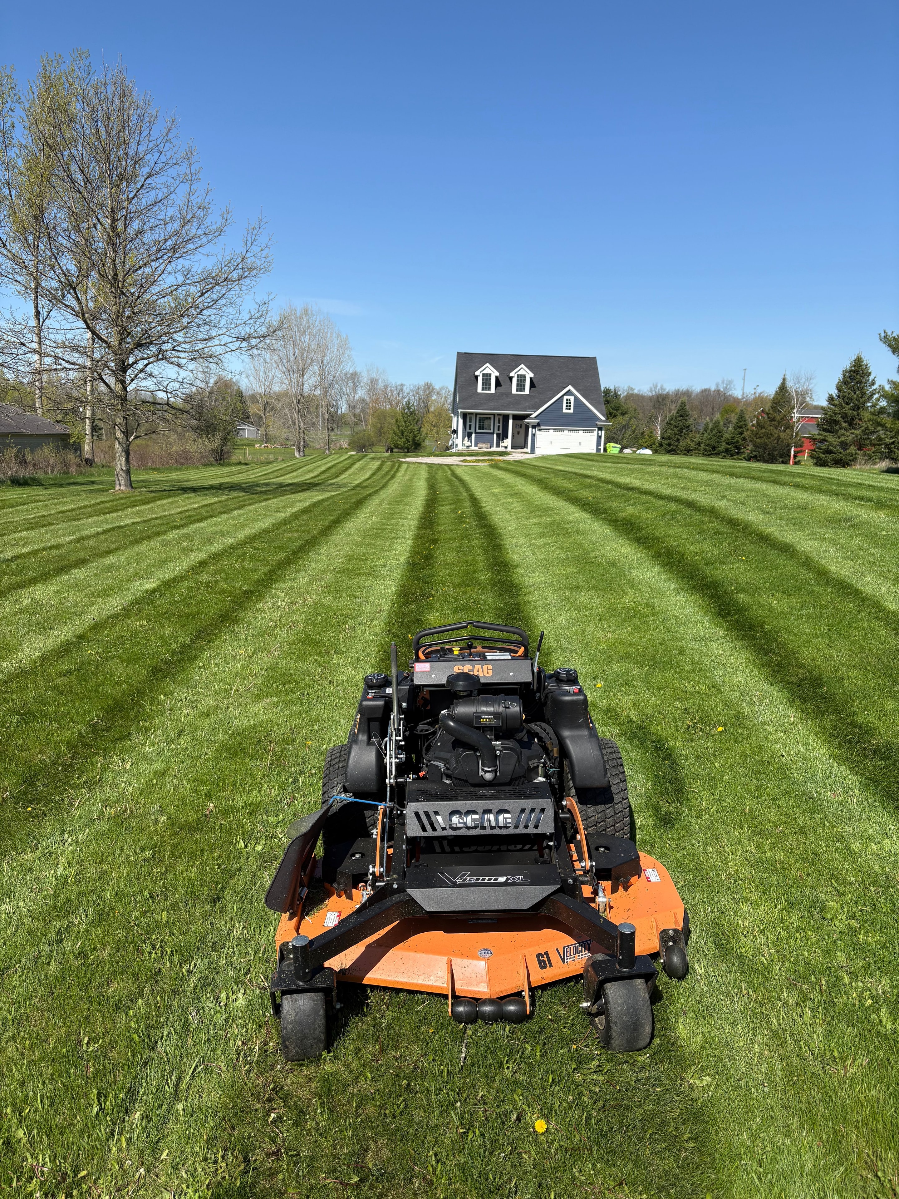 SCAG Velocity XL leaving ruler-straight stripes on a large hillside property.